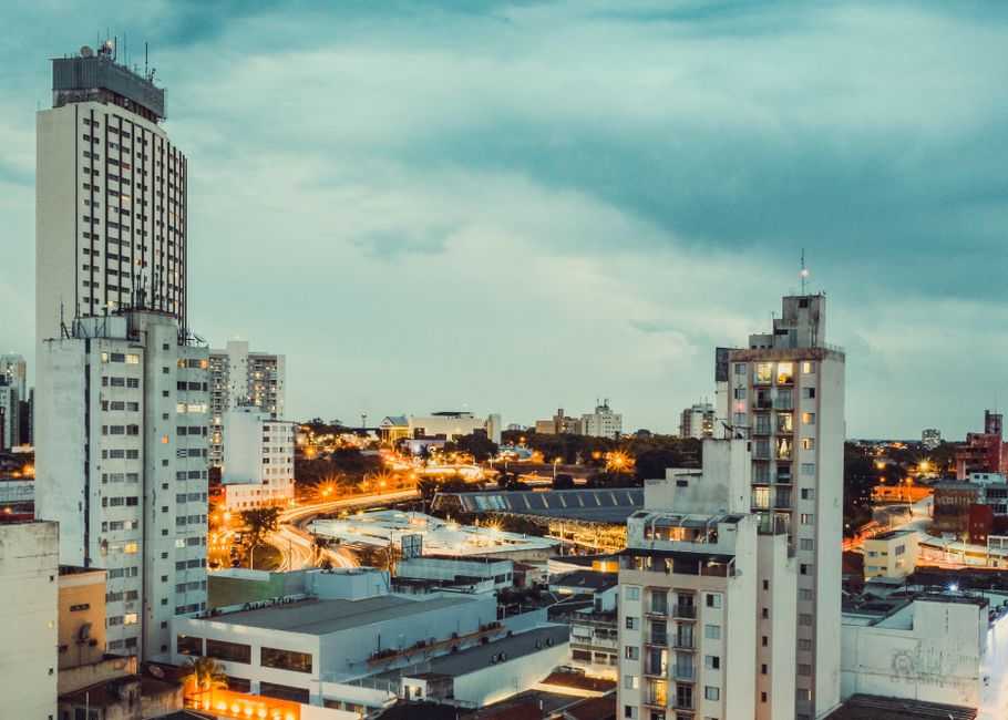Foto ilustrativa de prédios residenciais e avenida iluminada ao entardecer em Campinas