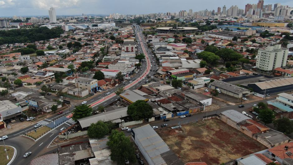 Vista aérea de avenida movimentada cortando bairros residenciais de Campinas, com prédios ao fundo