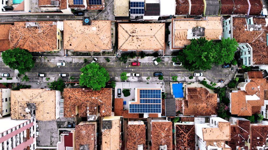 Vista aérea de rua residencial com casas de telhado cerâmico e árvores, foto ilustrativa