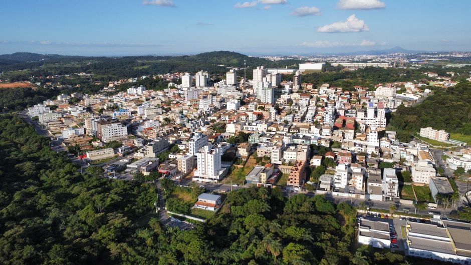 Vista aérea ilustrativa de bairro com prédios e casas cercados por mata nativa