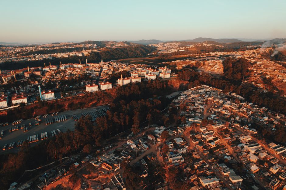 Foto ilustrativa aérea de bairros residenciais com prédios e casas ao entardecer